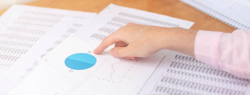 female accountant making calculations sitting at office table with documents with tables on desk pointing at digits on documents. Savings, finances and economy concept, working with documents, banner
