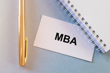 İş eğitimi konsepti. Ofis masasında MBA kısaltması olan beyaz kağıt kart. Spiral defter, altın kalem, düz çizgi, işletme yönetimi ustası..