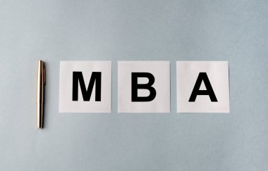 İş eğitimi konsepti. MBA kısaltmalı beyaz kağıtlar mavi gri ofis masasında gümüş kalemli, düz, işletme yönetimi ustası.