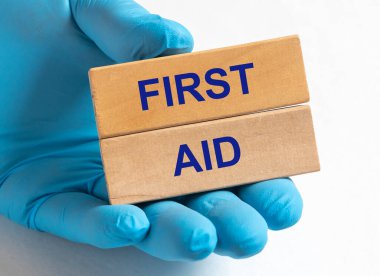 Doktorun elindeki ahşap bloklara yazılan ilk yardım mesajı beyaz masanın üzerinde mavi eldivenlerle..