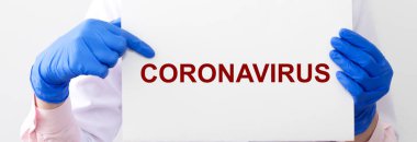 Koronavirüs kavramı. 2019-nCoV yazıt beyaz kağıt üzerinde koruyucu eldivenler içinde doktor ellerinde.