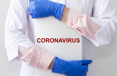 Koronavirüs kavramı. 2019-nCoV yazıt beyaz kağıt üzerinde koruyucu eldivenler içinde doktor ellerinde.
