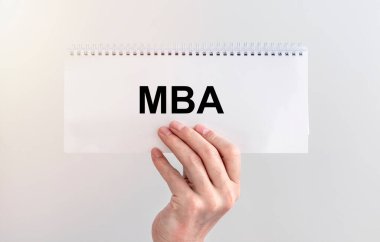 İş eğitimi konsepti. Beyaz sarmal üzerinde MBA kısaltması beyaz duvarın üzerinde erkek eli tutan bir defter..