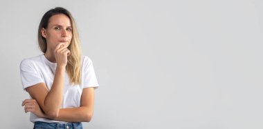 Şüpheli bir kadının çenesine parmak attığını, stusio potrait 'in gri arka planda olduğunu düşünüyor. kopyalama alanı, afiş