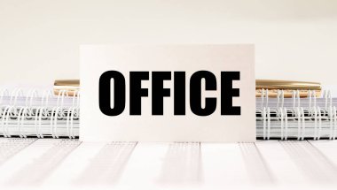 Masada beyaz kağıt üzerinde evrak ve kalemle ofis kelimesi.