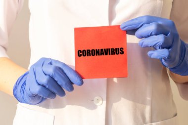 Coronavirus COVID kelime kırmızı kağıt üzerinde Kadın ellerinde koruyucu eldivenler.