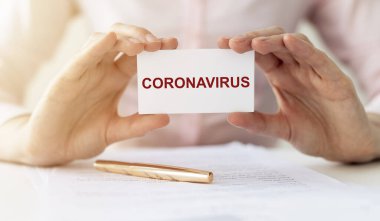 Coronavirus COVID kelime beyaz kağıt üzerinde kadınların ellerinde belgeler ve kalem ile masada.