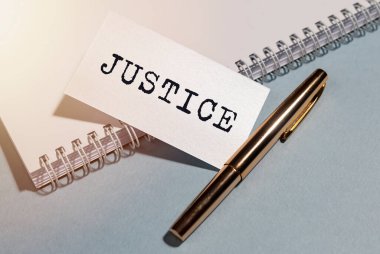 Ofis masasında beyaz kağıt üzerine yazılmış adalet kelimesi. Pankart, yakın plan