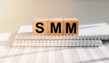 SMM, sosyal medya pazarlaması, ofis masasında dökümanlarla birlikte tahta küpler üzerindeki kelime kısaltması..