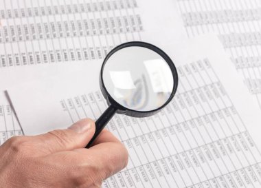 Üzerinde büyüteç bulunan mali belgeler erkeklerin elinde, iş araştırmaları konsepti. Kapat.