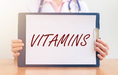 Beyaz kağıt tahtadaki vitaminler doktorun eline geçti. sağlık kavramı.
