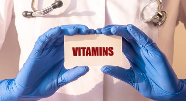 Beyaz kağıt tahtadaki vitaminler doktorun eline geçti. Sağlık konsepti. Kapat.