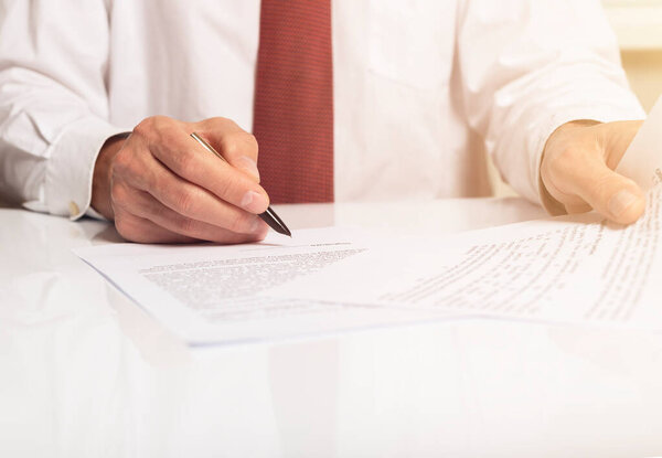 Contract signing concept. Businessman hand with pen over document closeup.