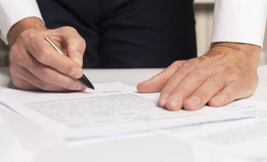 Sözleşme imzalama konsepti. Belgeyi yakın plan üzerine yazan iş adamı eli.