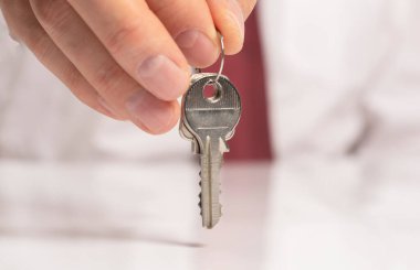 Kravatlı bir işadamının eli, beyaz masanın üzerinde duran ve yansıması olan yeni bir daireden anahtar veriyor..