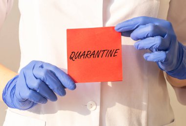 Kelime QuaranTINE kağıt üzerinde doktorun ellerinde koruyucu eldivenler içinde beyaz arka plan üzerinde. tıbbi tecrit kavramı