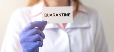 Kelime QuaranTINE kağıt üzerinde doktorun ellerinde koruyucu eldivenler içinde beyaz arka plan üzerinde. tıbbi tecrit kavramı