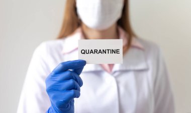Kelime QuaranTINE kağıt üzerinde doktorun ellerinde koruyucu eldivenler içinde beyaz arka plan üzerinde. tıbbi tecrit kavramı
