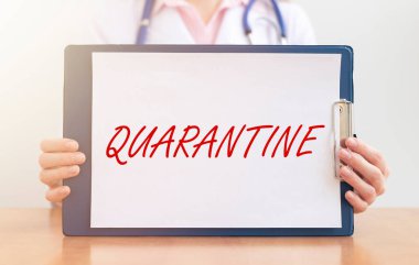 Kelime QuaranTINE kağıt üzerinde doktorun ellerinde koruyucu eldivenler içinde beyaz arka plan üzerinde. tıbbi tecrit kavramı