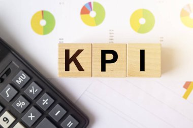 KPI, şirket hedef kavramı için Anahtar Performans Göstergesi, kübik bloklar hesap makinesiyle yıllık renkli grafikler ve grafik raporları üzerinde kısaltma oluşturur