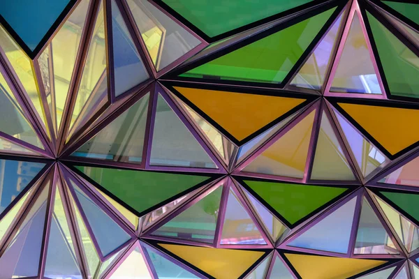 Colourful triangular patterned glass roof, with green, yellow and blue segments.