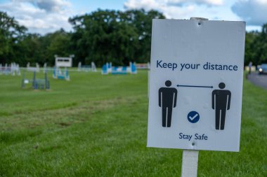 Koronavirüs İngiltere 'de tecrit kolaylaşırken insanlardan sosyal olarak uzak durmalarını ve açık hava binicilik etkinliklerinde güvende olmalarını isteyen bir işaret.