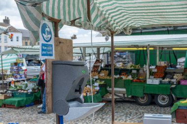 Richmond, Kuzey Yorkshire, İngiltere - 1 Ağustos 2020: Bir açık hava pazarının girişinde müşterilerin Coronavirus önlemi olarak içeri girdiklerinde ellerini yıkamalarını sağlayan bir tabela ve bir yıkama istasyonu