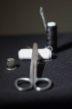 Dikiş makası, yüksük yakın plan, siyah zemin üzerinde beyaz iplikler, siyah iplikle dikiş, iğne zanaat