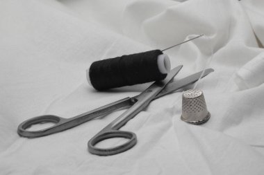 Siyah iplik makarası ve beyaz arka planda iğne ve yüksük ile beyaz iplik makarası.