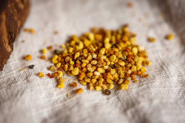 Arı ürünlerini kapatın. Sarı turuncu sağlıklı polenler. Arıların keten kumaş masa örtüleri üzerinde topladığı polenler.