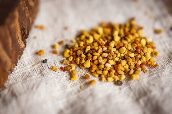 Arı ürünlerini kapatın. Sarı turuncu sağlıklı polenler. Arıların keten kumaş masa örtüleri üzerinde topladığı polenler.