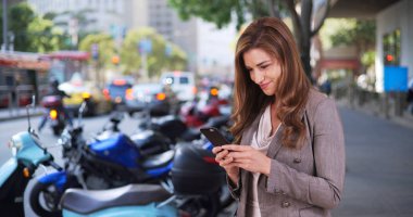 Seksi iş kadını stajyer ekip üyelerinin uzaktan iletişim kurmak için Smartphone kullanarak