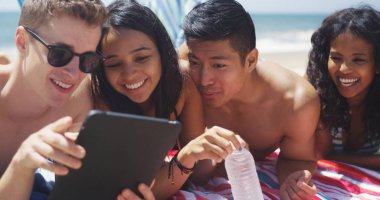 Genç Interracial Grup dört arkadaşıyla sahilde tablet izlerken