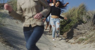 Gülüyor ve Plaj kumlu tepeden aşağı çalışan arkadaş grubu