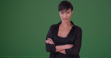 Young black woman in black outfit looking somber at the camera on green screen clipart