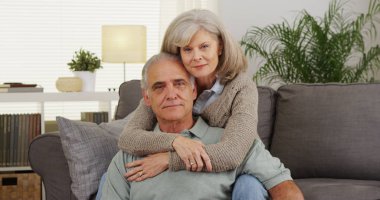 Kameraya bakarak oturarak Olgun çift kanepe