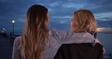 İki kadın arkadaş dost birlikte iskele alacakaranlıkta paylaşmak