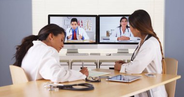 Professional team of multi-ethnic medical doctors having a video conference clipart