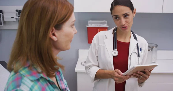 Attraktive Hispanische Ärztin Mit Tablette Notizen Von Älteren Patientin Machen — Stockfoto