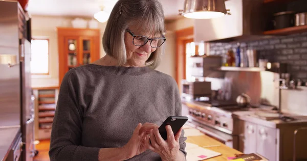 Happy Senior Woman Sending Text Messages Domestic Kitchen Setting — Stock Photo, Image