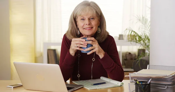拿着咖啡的老年妇女微笑的笔记本电脑 — 图库照片