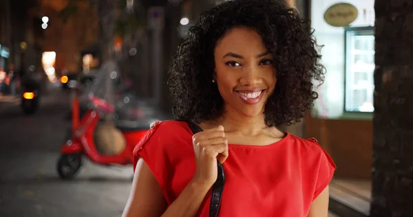 Happy African American woman tourist smiling on charming Italian street at night