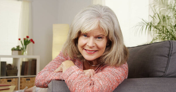 Зрелая женщина улыбается и смотрит в камеру дома
