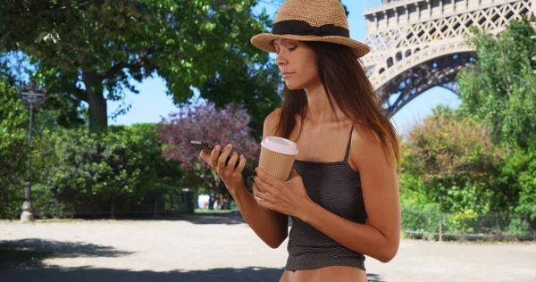 漂亮的旅游妇女拿着咖啡在埃菲尔铁塔附近发短信 — 图库照片