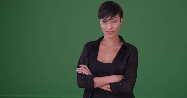 Young black woman in black outfit looking somber at the camera on green screen