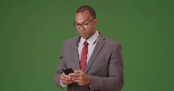 一名黑人在绿屏上用手机做生意 — 图库照片