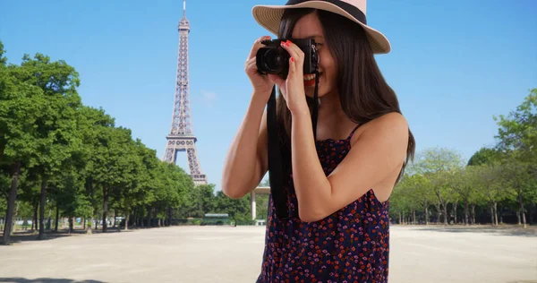 Closeup of Asian millennial photographer taking photos by Eiffel Tower in Paris
