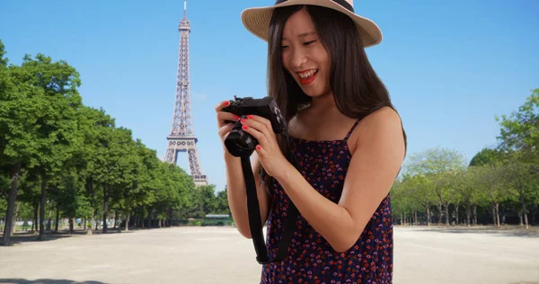 Closeup of Asian millennial photographer taking photos by Eiffel Tower in Paris