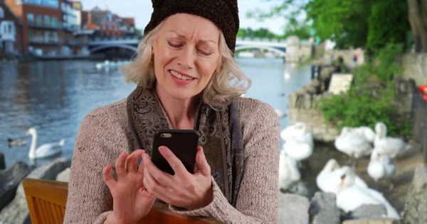 Senior Vrouw Bankje Door Rivier Windsor Kijken Naar Mobiele Telefoon — Stockfoto