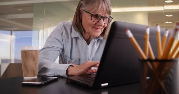 Šťastná Starší Žena Pomocí Přenosného Počítače Uvnitř Moderní Kancelářské Prostředí — Stock fotografie